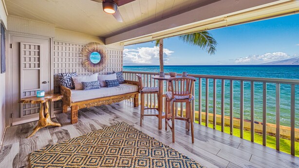 Ein Balkon mit Holzboden, einer Couch, zwei Stühlen, einem Tisch und einem Deckenventilator.