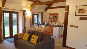 Un salon confortable avec un canapé, une table à manger et un coin cuisine doté de meubles en bois et d’un réfrigérateur.