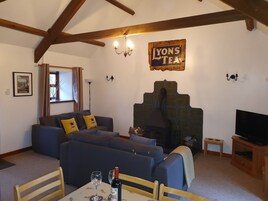 A cozy living room with a sofa set, a fireplace, a television, and a table with a bottle and glasses.