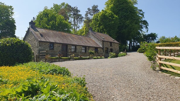 Un bâtiment en pierre avec une allée de gravier menant à un portail en bois.