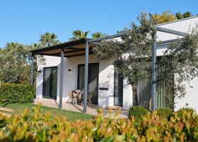 Una casa moderna con un porche cubierto, amplias ventanas y un jardín cuidado.