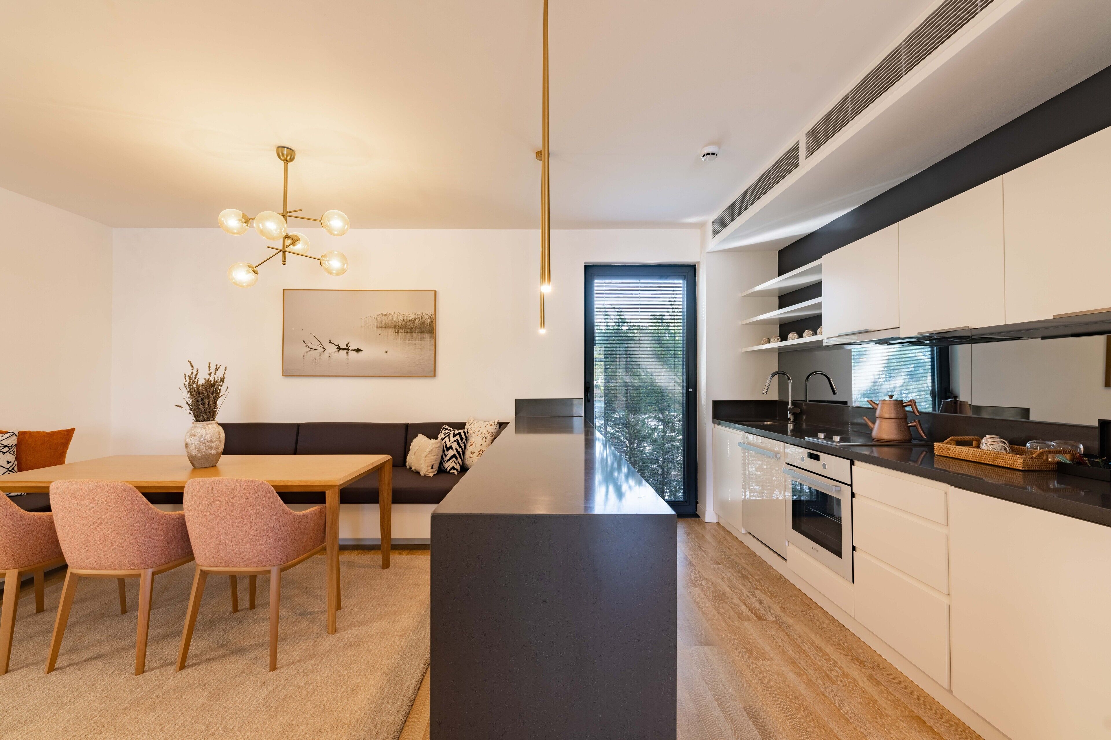 A modern kitchen with a central island, built-in appliances, and a dining area with a sofa and chairs.