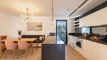 A modern kitchen with a central island, built-in appliances, and a dining area with a sofa and chairs.