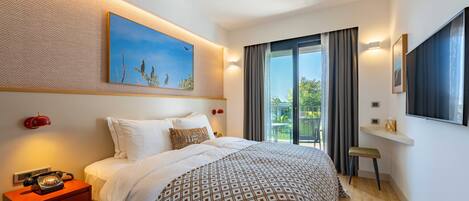 A modern hotel room with a large bed, a nightstand with a telephone, a painting on the wall, a window with curtains, and a view of greenery outside.