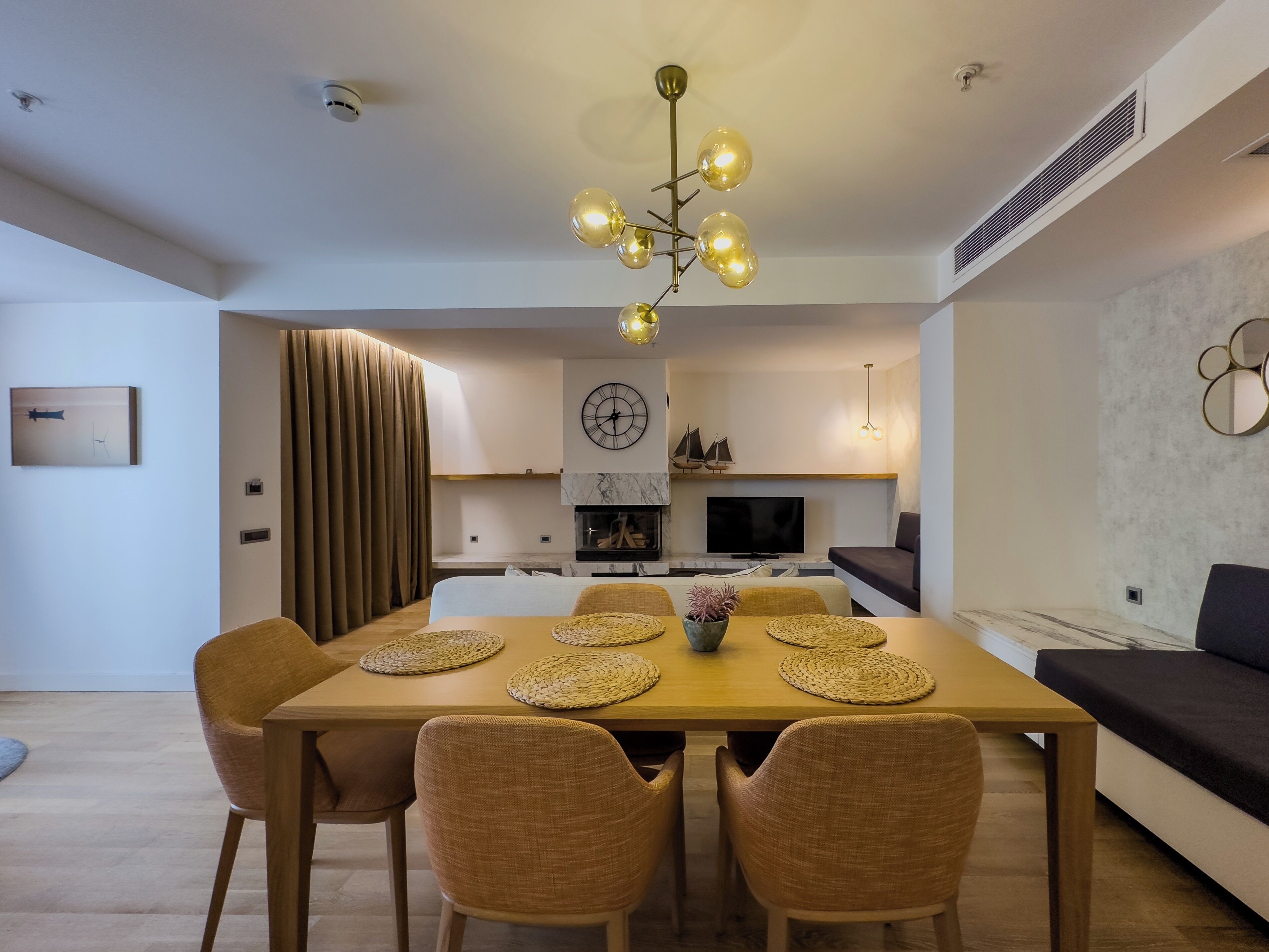 A modern dining area with a wooden table, woven placemats, and wicker chairs.