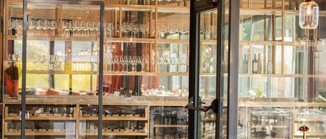 A wine cellar with shelves of wine bottles and glasses.