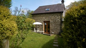 A stone house with a wooden door, a small window, and a white umbrella outside. - Ty Twt (Lampeter)