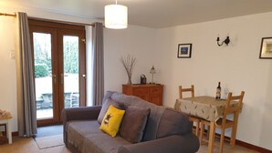 A living room with a sofa, a dining table with chairs, a lamp, and a picture on the wall. - Ty Twt (Lampeter)