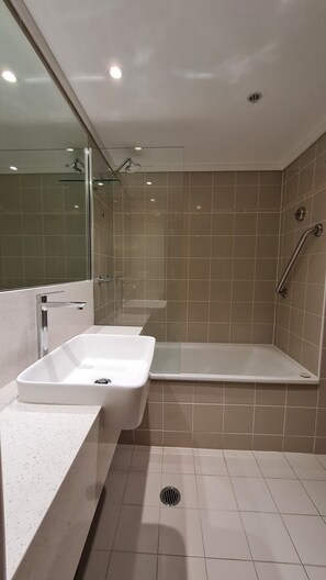 Enjoy a refreshing shower in the bathroom, featuring a glass-enclosed shower area with a handheld showerhead and wall-mounted faucet.