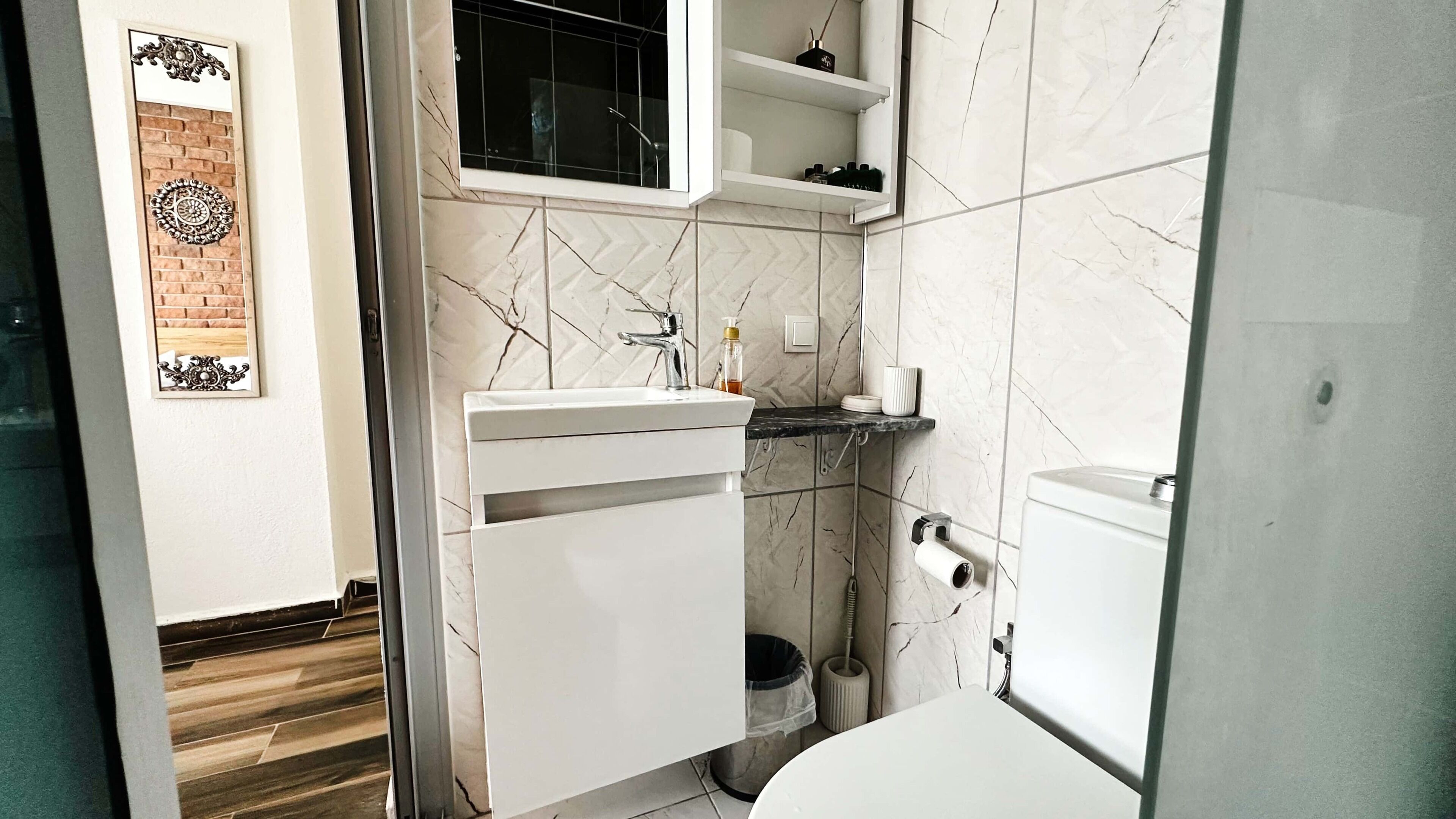Uma casa de banho moderna com lavatório branco, sanita e zona de duche.