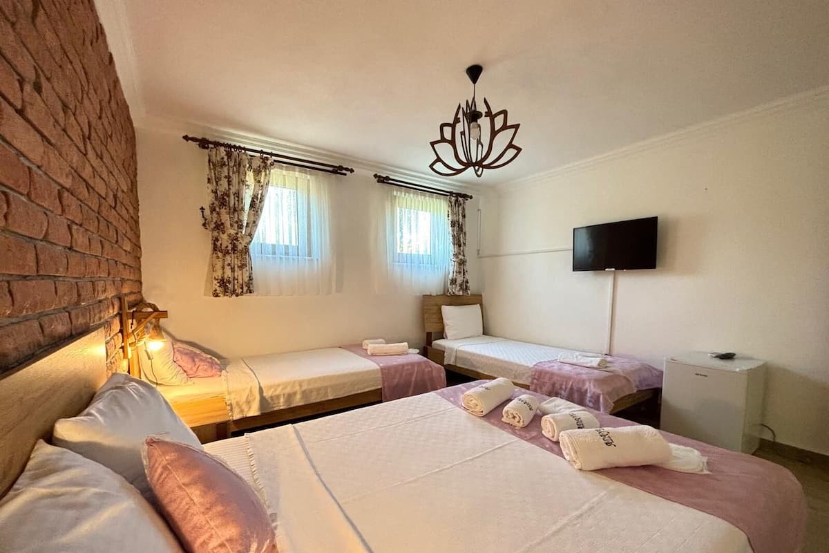 A hotel room with two beds, a TV, and a brick wall.