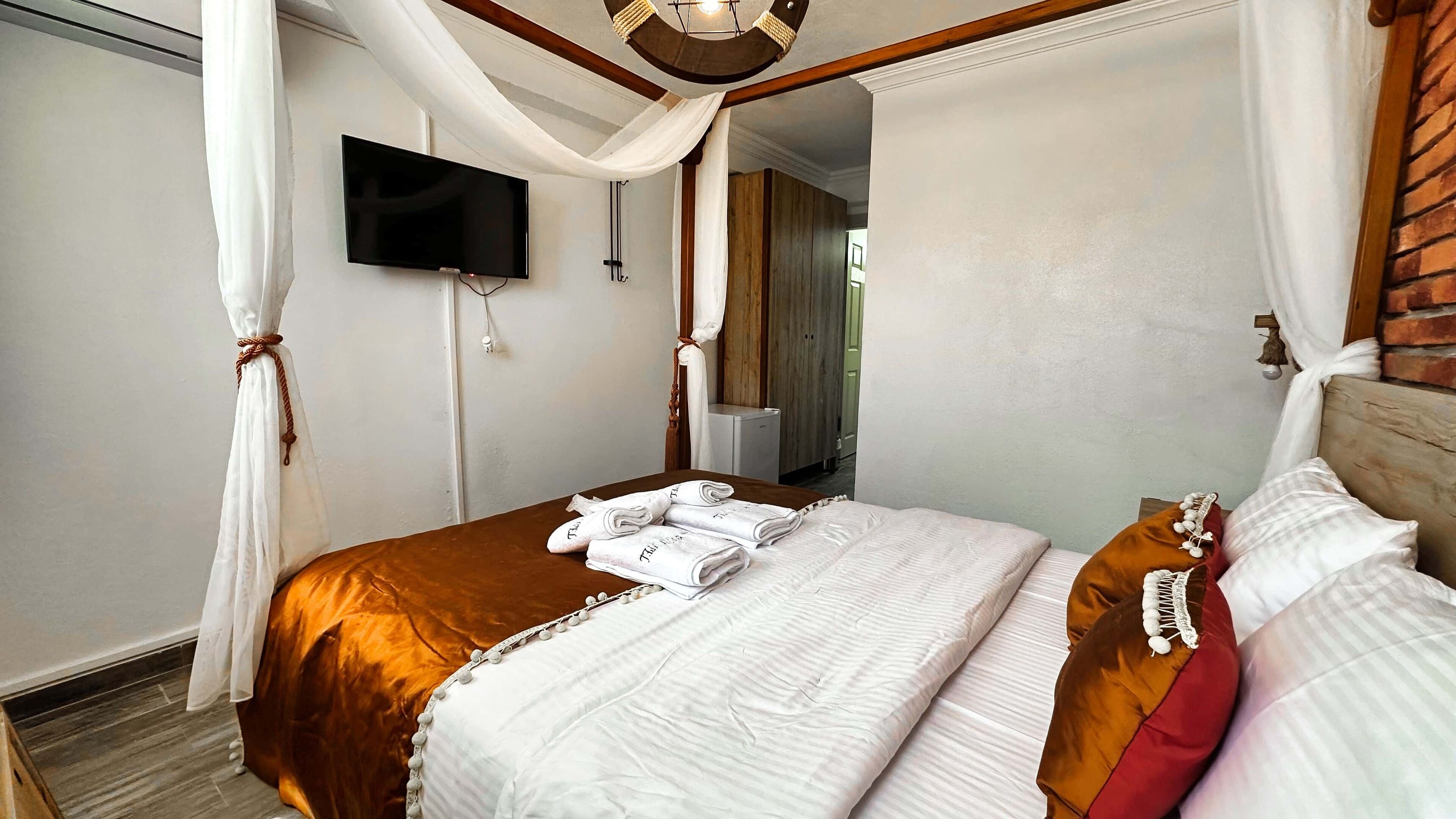 A bedroom with a bed, a TV, and a bathroom visible in the background.