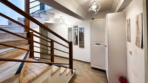 Un intérieur moderne avec un escalier, une porte et des œuvres d’art accrochées au mur.