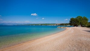 Una playa con agua turquesa cristalina, una orilla arenosa y algunos árboles.