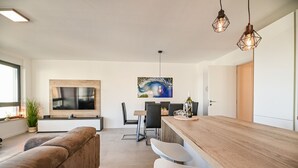 Una sala moderna con un televisor grande, una mesa de comedor de madera y un rincón de descanso acogedor.