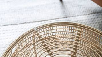 Una cesta de mimbre con diseño circular, sobre una alfombra texturizada.