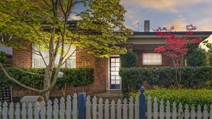 A brick house with a white picket fence, a mailbox, and a number '133' on the door. - Heritage on Hill - Refreshing Elegance (Orange)
