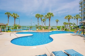 A pool area with multiple swimming pools, lounge chairs, and palm trees.