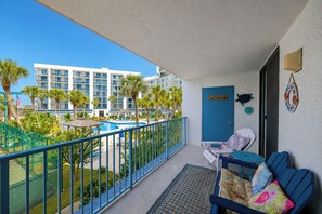 A balcony with a pool view, a door, and a seating area with cushions.