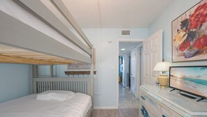Una habitació amb una llitera, un taulell amb una làmpada i un quadre a la paret.
