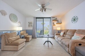 A living room with two sofas, a table, and a ceiling fan.