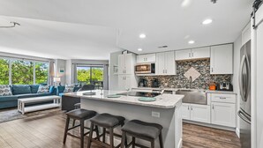 A modern kitchen with white cabinets, a granite island, and stainless steel appliances. - Coastal 2BR Villa w/ Balcony & Amenities (Hilton Head Island)