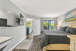 Quarto com cama, televisão, escrivaninha e varanda com vista.