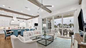 A spacious living area with a modern kitchen, large windows, and a ceiling fan. - Seagrove Sparrow|Easy Beach Access|Private Pool|Outdoor Oasis (Santa Rosa Beach)