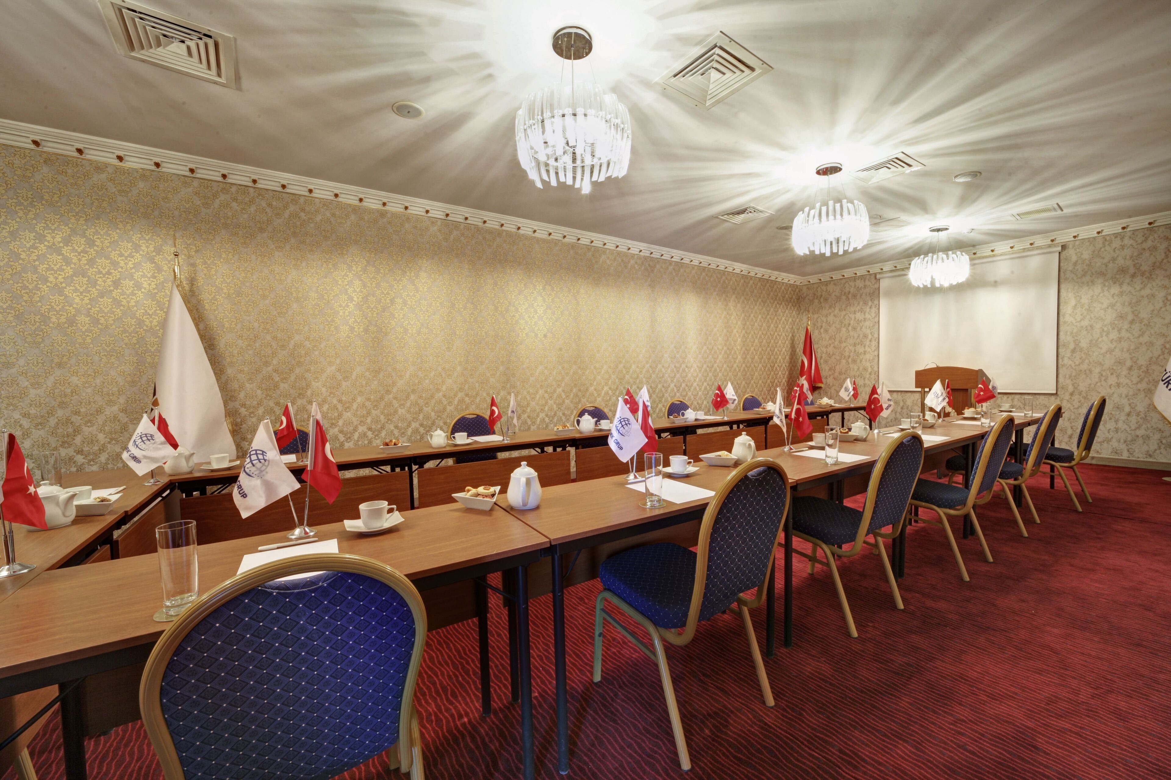 Un salón de conferencias con varias mesas, sillas y banderas.