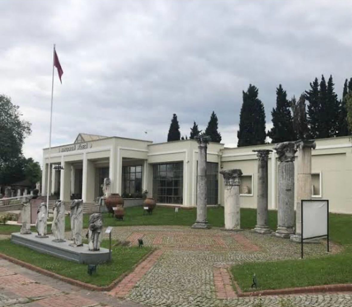 Un edificio de arquitectura clásica, con columnas y un asta de bandera.