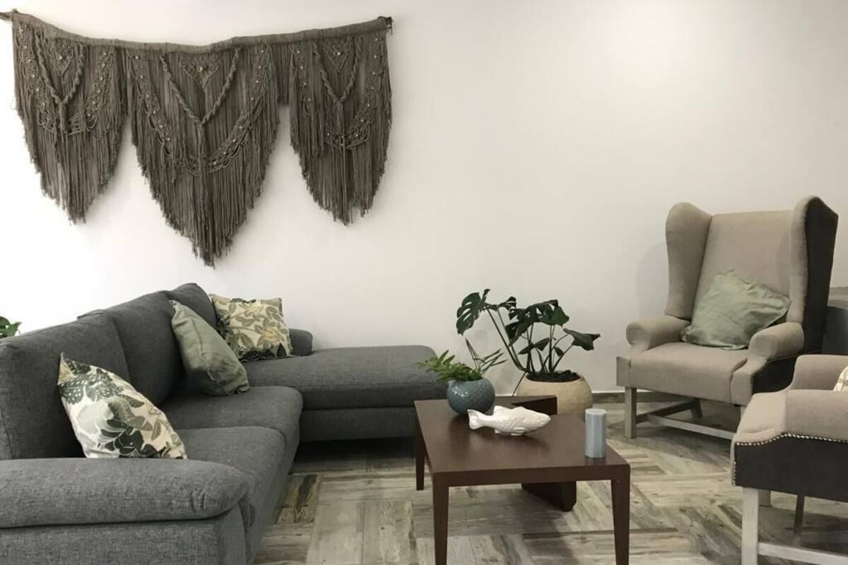 A living room with a grey sofa, a beige armchair, a coffee table, and a potted plant.