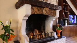 Una chimenea con detalles de piedra, un televisor montado en la pared y un estante de madera con objetos decorativos.