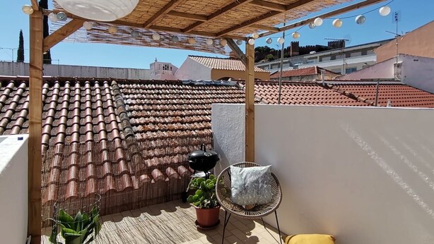 A rooftop terrace with a thatched roof, potted plants, and a hanging light fixture. - Algarve house, sun, terrace, views and barbecue (Silves)