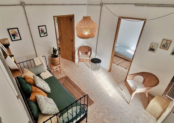 Uma sala de estar ampla com sofá, cadeiras, luminária pendente e um espelho grande.