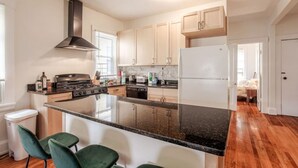 A modern kitchen with a central island, stainless steel appliances, and light wood cabinets. - The Villa Emerald 1B Walk to Downtown Covington (Covington)