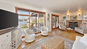 Un salon spacieux doté d’une cheminée, de grandes fenêtres et offrant une vue sur l’extérieur.