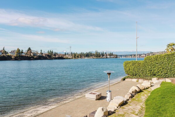 A waterfront property with a patio, a lamp post, and a view of the water and mountains. - Waterfront Beach Cottage (Bremerton)