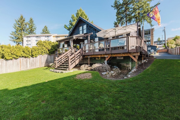 A two-story house with a deck, stairs, and a flag. - Waterfront Beach Cottage (Bremerton)