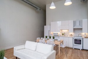 Una cocina moderna con armarios blancos, un microondas, un horno y un comedor con mesa y sillas blancas.