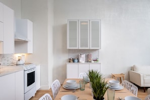 A modern kitchen with white cabinetry, a stove, and a dining area with a table set for two.