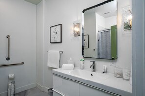 Un baño moderno con un lavamanos blanco, un espejo y un perchero para toallas.