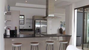 A modern kitchen with a central island, stainless steel appliances, and bar stools.