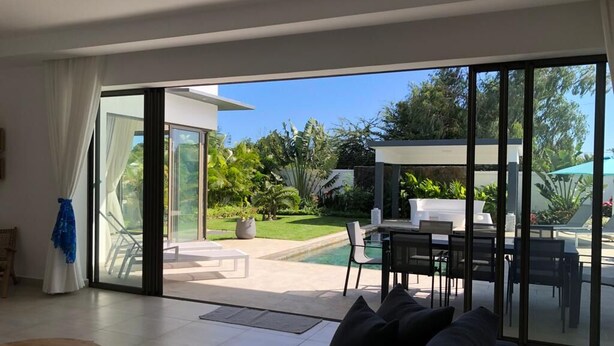 A modern living room with a large sliding glass door leading to an outdoor patio area.