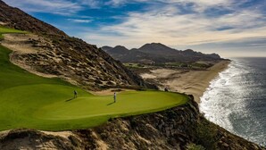 A coastal golf course with a view of the ocean and distant mountains. - 2 BR Stunning Ocean Views Condo · Copala Quivira (Cabo San Lucas)