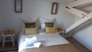 A bedroom with a bed, two nightstands, a wooden chest, and a staircase. - Apartment T3 ❤de ville. (La Rochelle)