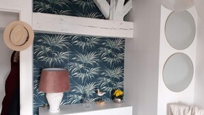 A room with a patterned wallpaper, a white dresser, a lamp, and a hat hanging on the wall. - Apartment T3 ❤de ville. (La Rochelle)