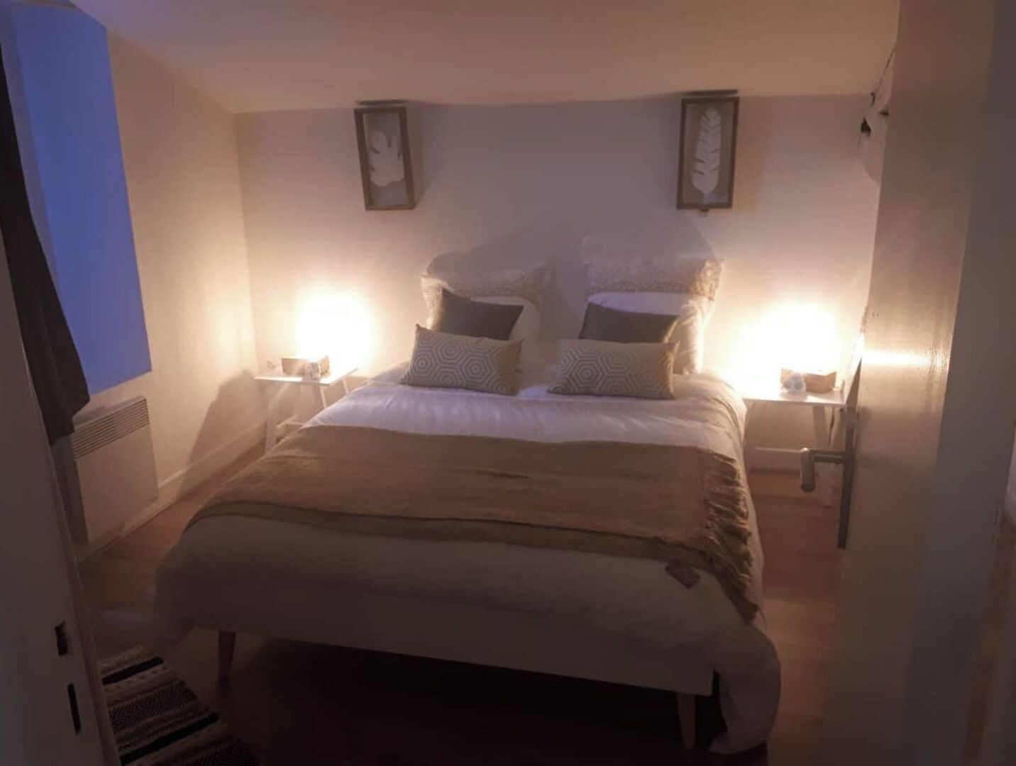 Un dormitori amb un llit gran, dues taules de nit i dues làmpades penjades a la paret.