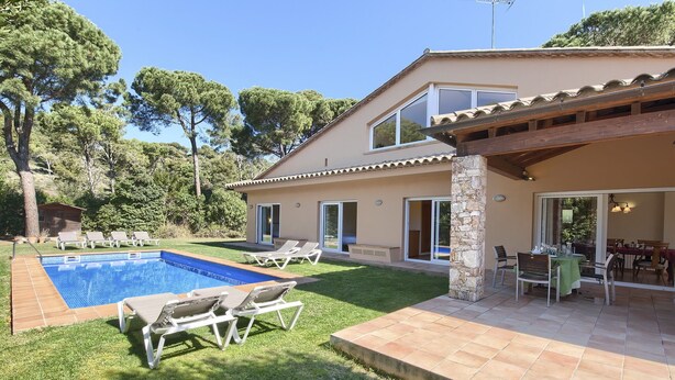 A two-story house with a swimming pool, outdoor seating, and a patio area.