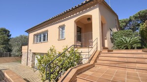 A two-story building with a tiled roof, a stone base, and a balcony with metal railings.