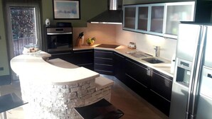 Una cocina moderna con una isla de piedra, electrodomésticos de acero inoxidable y muebles oscuros.
